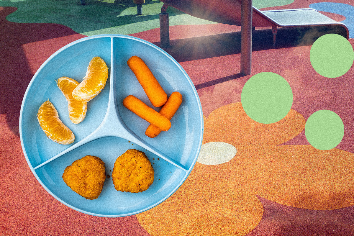 A divided plate with chicken nuggets, baby carrots and citrus slices on a background of colorful a playground surface