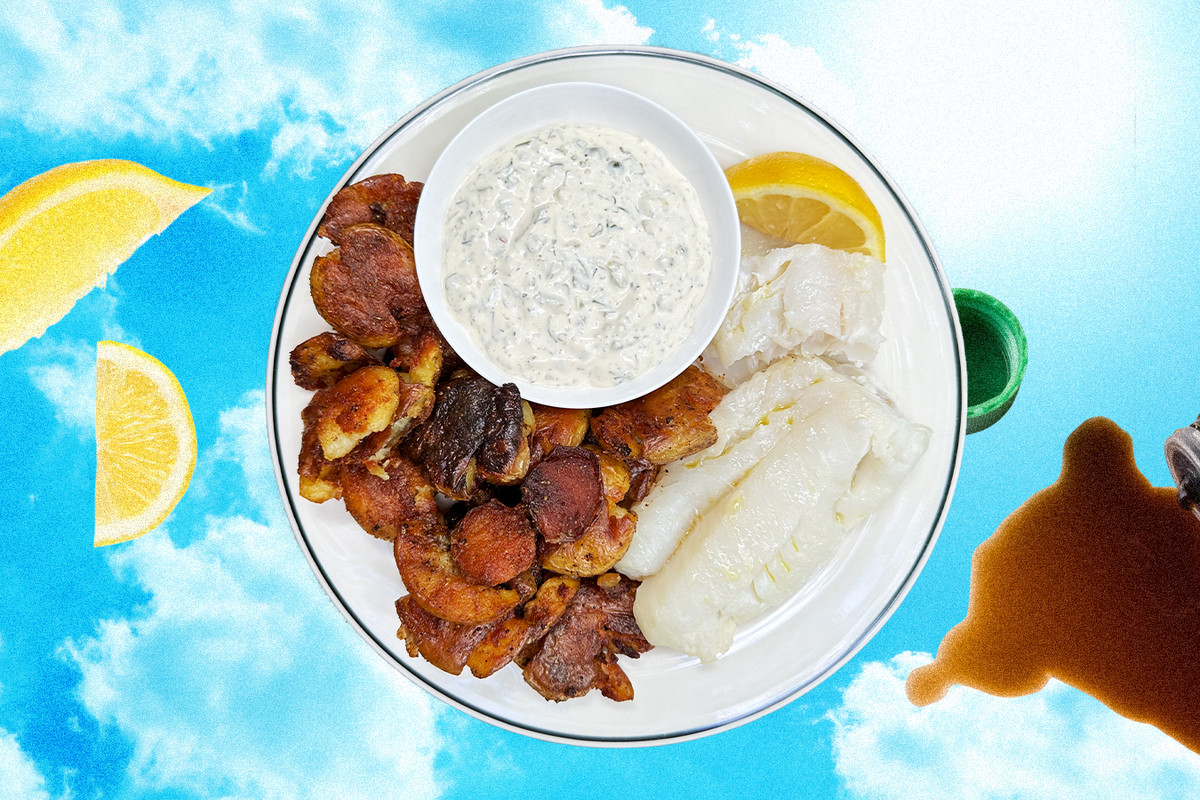 A plate of cod and fried potatoes and tartar sauce, garnished with a lemon on a cloudy sky backdrop