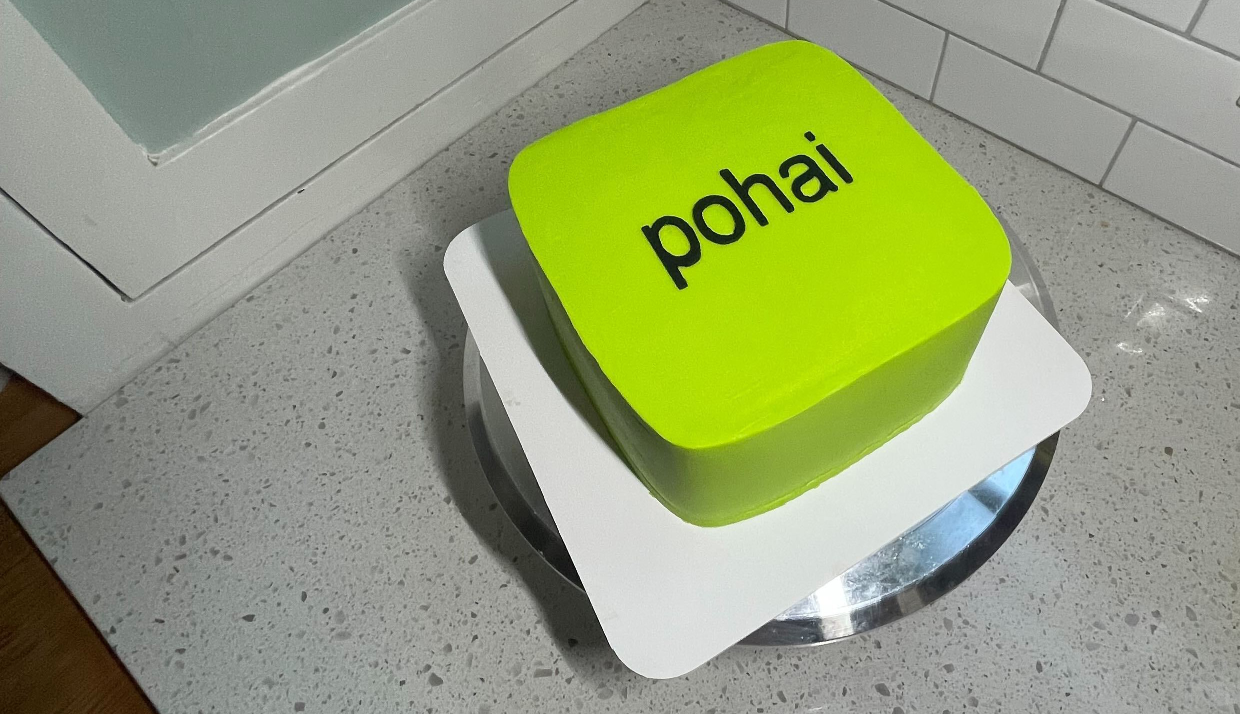 A bright green cake with the name Pohai on it in black lettering